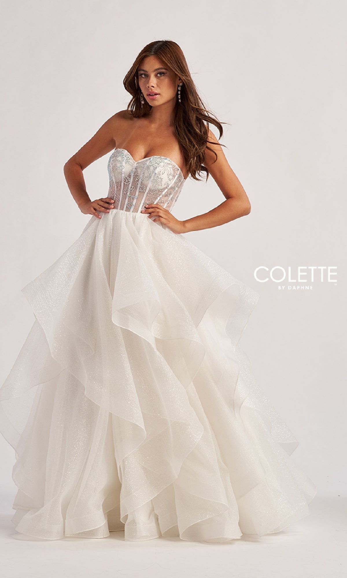A woman models the Colette CL8200 Long Prom Ball Gown, featuring a strapless beaded corset bodice and ruffle tiered glitter tulle skirt, standing against a plain background with
